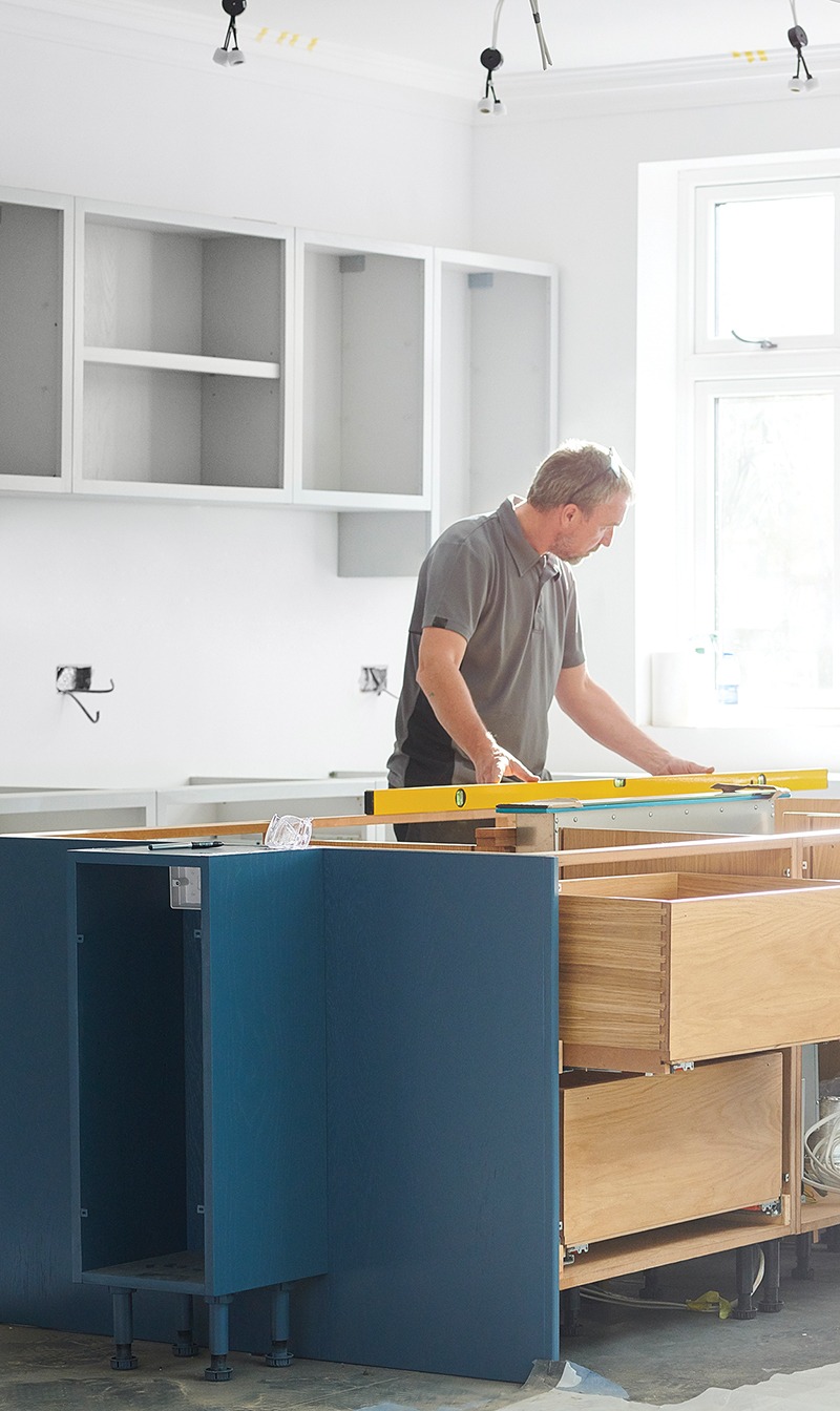 This image shows a man installing a kitchen.